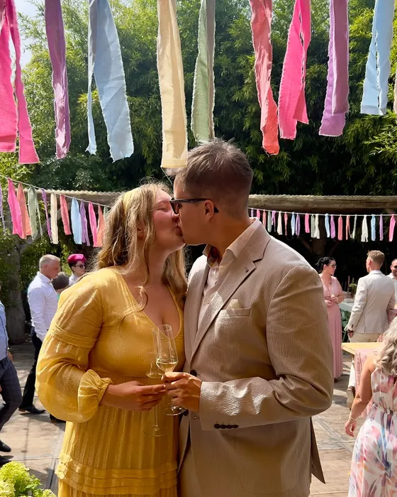 Stan en Nina geven elkaar een kus onder kleurrijke slingers